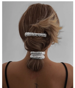 Détail d'un ensemble barrette et chouchou argenté avec texture en métal martelé