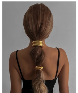 Détail de manchettes à cheveux en métal doré en forme de U sur une queue de cheval