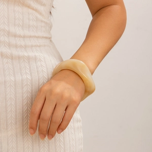 Minimalist wide wavy acrylic bangle in creamy beige tortoise shell style on model wrist