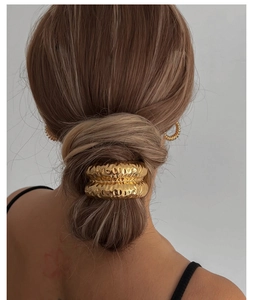 Détail de l'accessoire de cheveux doré texturé et boucles d'oreilles sur modèle