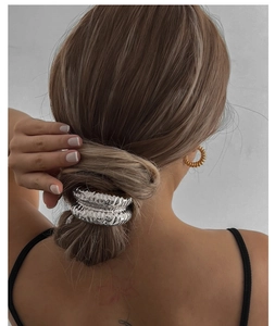 Élastiques à cheveux en métal argenté martelé portés en chignon, détail de la texture métal
