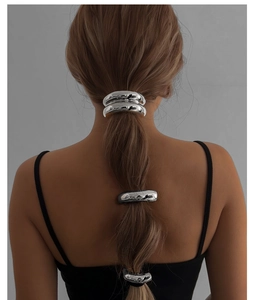 Close-up of three minimalist silver alloy hair rings with irregular wavy texture on ponytail