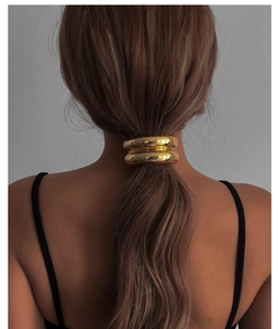 Detailed view of a shiny gold double-layered metal ring hair tie on a neat ponytail
