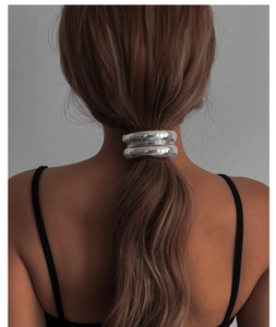 Detail view of a thick silver metal geometric ponytail holder on light brown hair