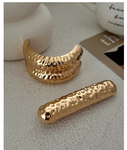 Détail d'accessoires de cheveux dorés avec texture martelée et finition brillante