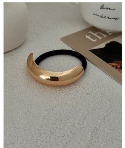 Close-up of golden curved metal buckle on high-elastic black ponytail holder