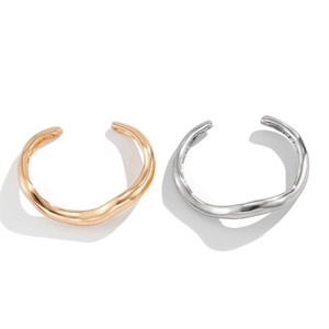 Minimalistische onregelmatige golvende open armbanden in goud en zilver op wit