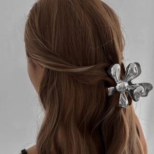 Polished silver metal flower hair claw clip on model's brunette hair in half-up style