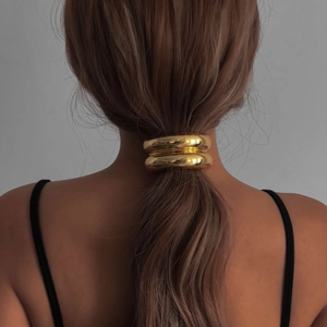 Polished gold double metal ring ponytail holder shown on a low ponytail hair style