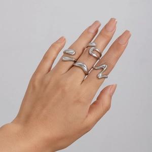 Detail of minimalist irregular silver rings with organic fluid shapes on model's hand
