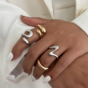 Macro shot of irregular wave rings in gold and silver finish on model's hand