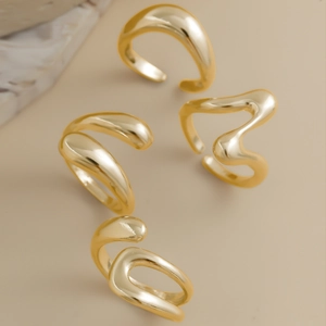 Detailed view of four golden fluid lava style rings with glossy metallic mirror finish