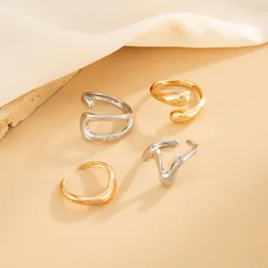 Detail of four gold and silver irregular geometric rings on silk fabric with stone props