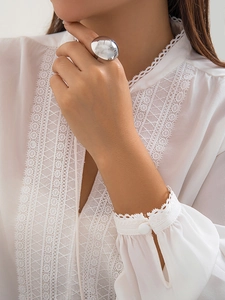 Close-up of a large silver oval ring with a polished mirror finish on a model's hand
