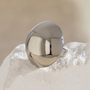 Macro shot of high-polish silver dome ring on white stone, showing mirror finish detail