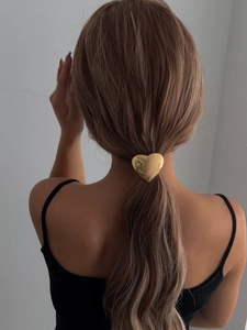 Gros plan d'un accessoire de cheveux en forme de cœur doré brillant sur une queue de cheval basse