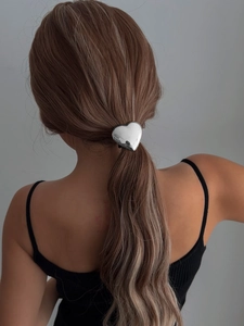Détail d'un élastique à cheveux en forme de cœur argenté avec une finition miroir