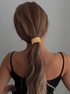 Détail d'un élastique à cheveux doré plissé en alliage pour une queue de cheval élégante