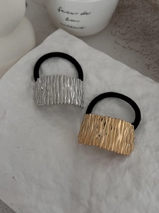 Détail d'élastiques à cheveux en métal doré et argenté sur un support en pierre