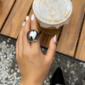 Minimalist silver mirror finish semi-circular metal ring in a lifestyle setting