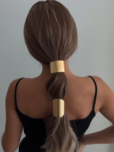 Detail of two golden minimalist geometric metal ponytail holders on styled hair