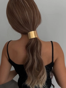 Close-up of a sleek golden cylindrical metal ponytail cuff for a minimalist hair look