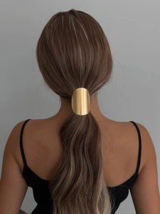 Detailed view of an oval gold metal hair cuff clip on a low ponytail hair style