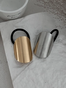 Detail view of matte gold and silver geometric oval metal hair ties on artistic background