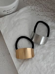 Macro detail of gold and silver matte brushed metal hair ties on textured background