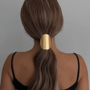 Glossy gold oval metal hair cuff accessory on a ponytail, minimalist geometric hair ring