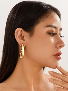 Nahaufnahme von Model mit dicken gedrehten Goldohrringen im unregelmäßigen Hohlraumdesign