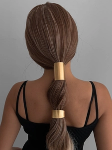Detail view of polished gold alloy metal hair cuffs on a low ponytail ponytail holder