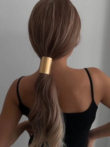 Detail of a matte gold metal hair cuff for ponytail styling on a fashion model