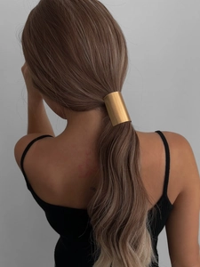 Close-up of a minimalist gold metal ponytail cuff hair ring with matte finish on model