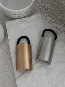 Detail of gold and silver brushed metal ponytail holders on a white stone background