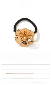 Detailed view of the layered metallic flower charm on a black elastic hair tie