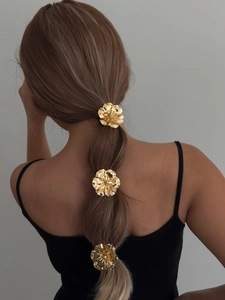 Close-up of three golden metallic flower hair ties styled on a ponytail back view