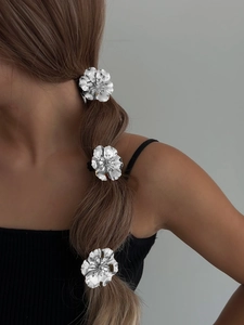 Close-up of three silver floral hair ties featuring textured alloy petals on a ponytail