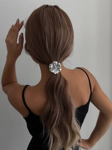 Detailed view of silver flower hair tie with textured petals on a ponytail