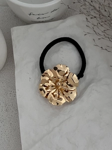 Detail of a large gold alloy flower with wrinkled texture on a high-elastic hair tie