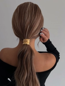 Dettaglio elastico per capelli in metallo dorato con finitura martellata per coda