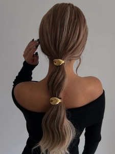 Dettaglio dell'anello per capelli in metallo dorato con design ovale minimalista