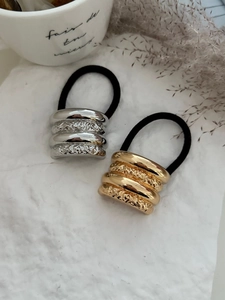 Dettaglio degli elastici per capelli in metallo martellato color oro e argento