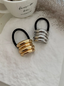 Elastici per capelli con anelli metallici oro e argento su sfondo di pietra bianca