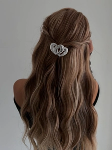 Vue détaillée d'une pince à cheveux argentée en forme de cœur sur de longs cheveux ondulés