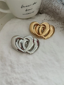 Détail de barrettes cœurs superposés élégantes en finitions or et argent polis