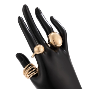 Detailed view of three polished gold rings including textured sphere and layered wrap styles