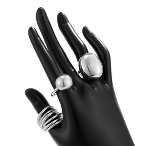 Three avant-garde silver metal rings featuring spiral and oval lava designs on a black hand