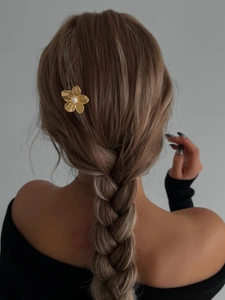 Detail of golden flower hair pin with pearl on braided hair showing summer style