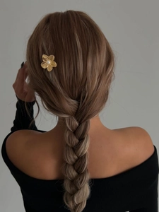 Detailed view of golden flower hair pin with pearl accent on braided hairstyle